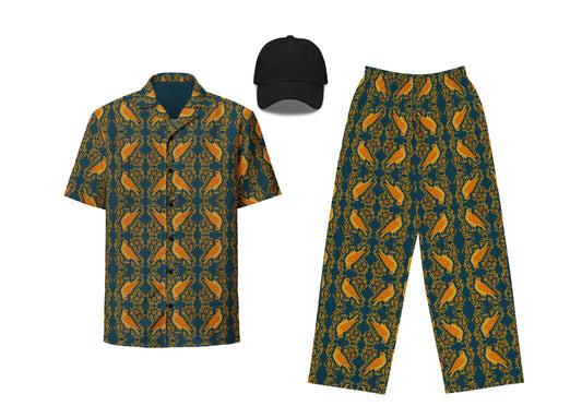 An outfit set including a button-up shirt and wide-leg pants with a blue and orange arabesque falcon pattern, paired with a black dad hat.