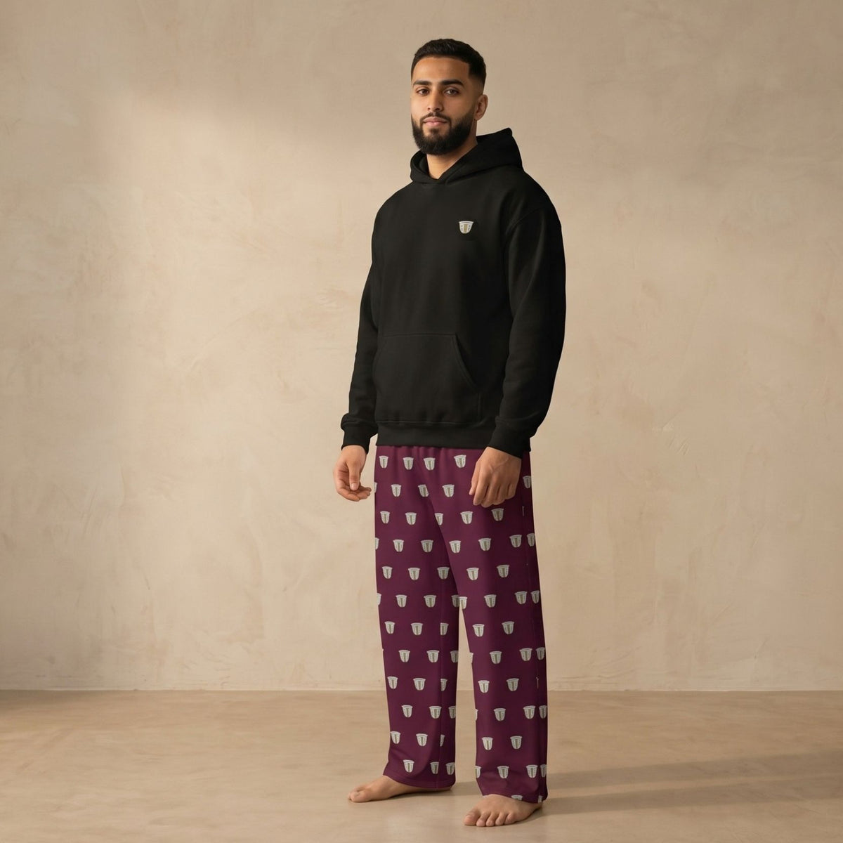 Model wearing a black hoodie with a small finjan motif and matching maroon pants with an all-over finjan print.