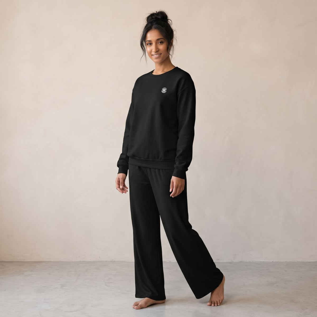 Model wearing a black sweatshirt with small pearl shell embroidery on the chest and matching black wide-leg pants.