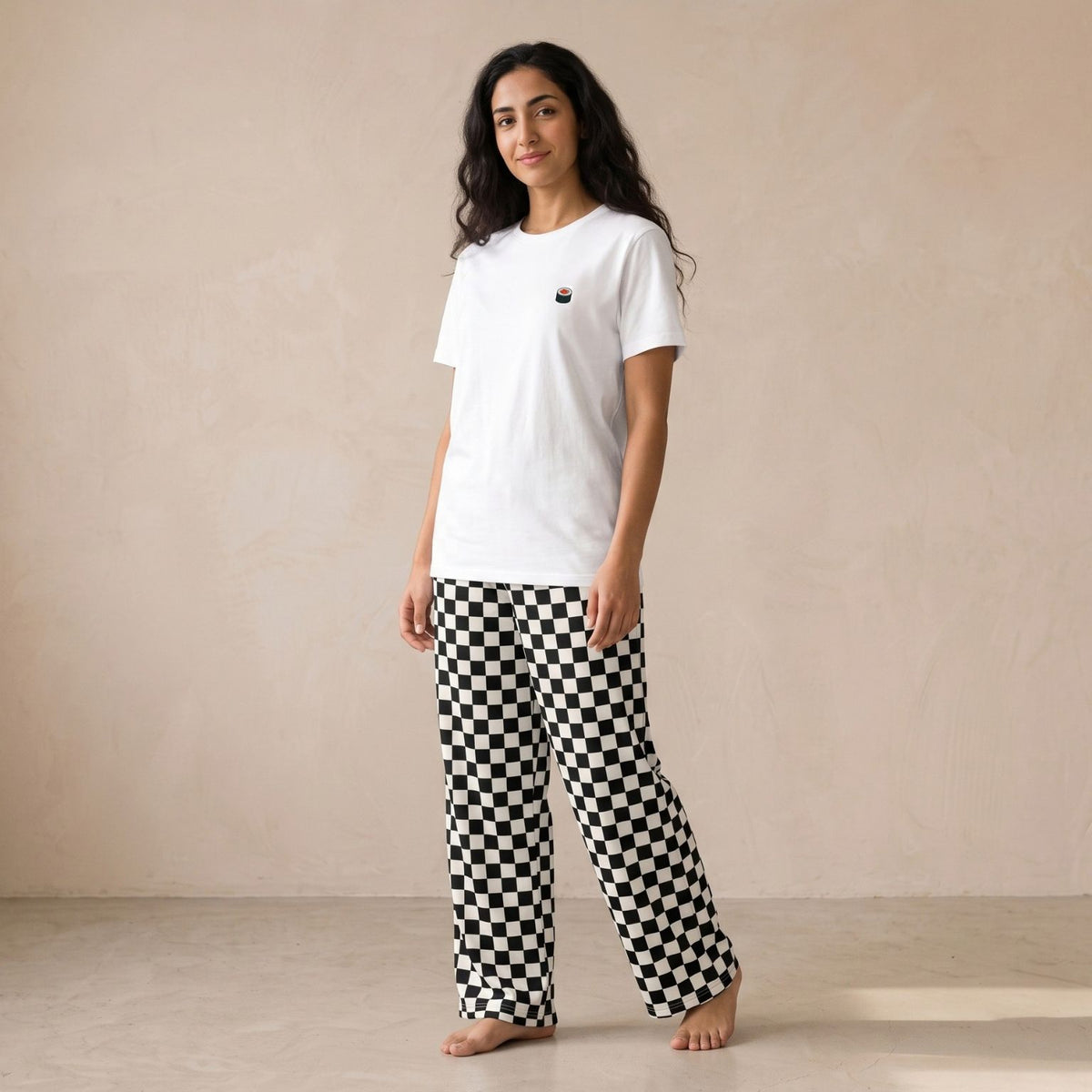 Model wearing a white T-shirt with a small sushi motif and black-and-white checkerboard pants, front view.