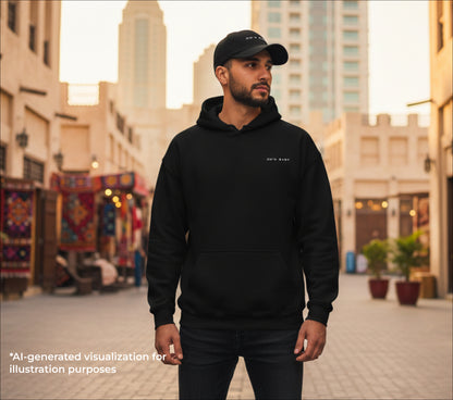 Man wearing a black hoodie and cap with an '00's baby' embroidery in an urban setting