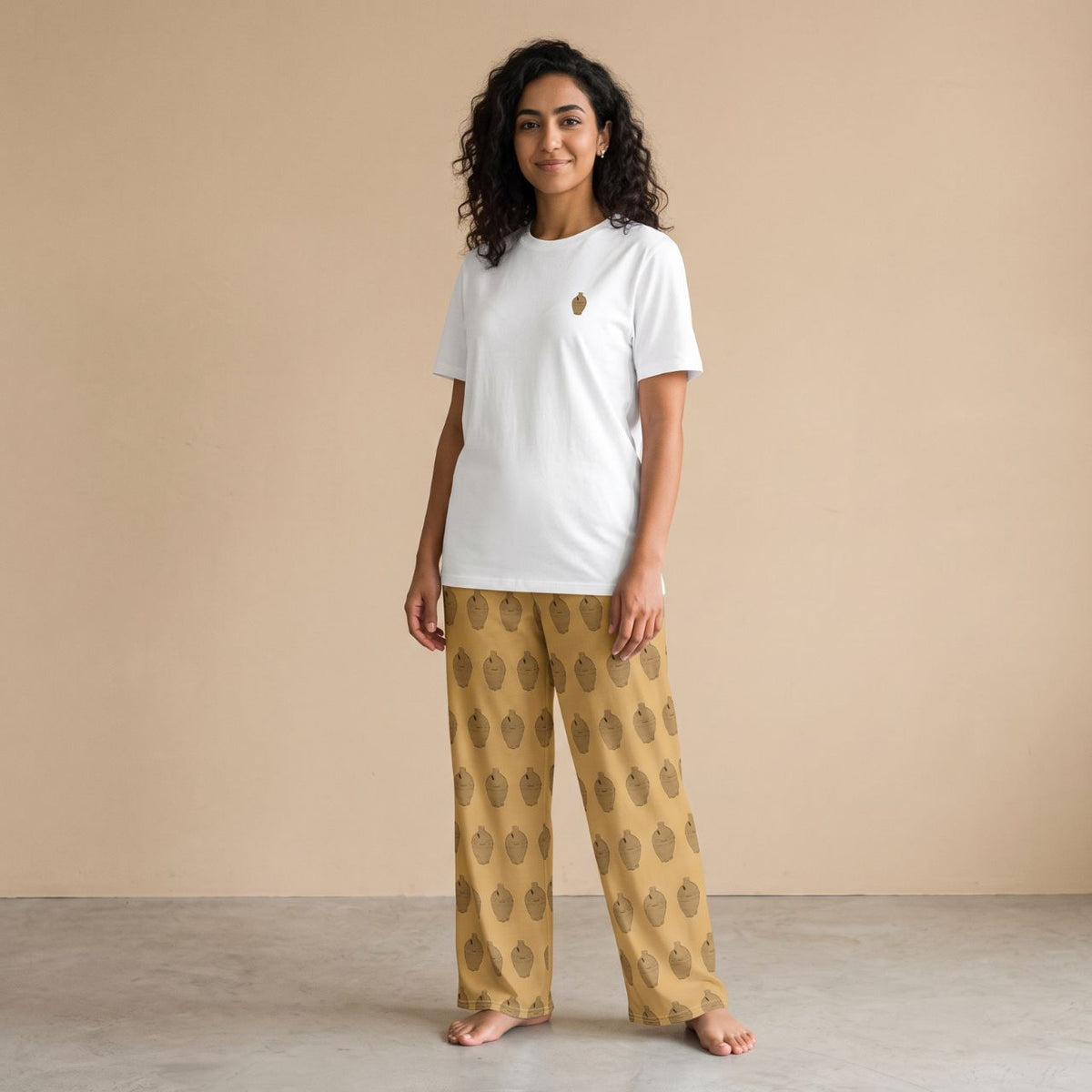 Model wearing a white T-shirt with a small traditional coin bank motif and mustard yellow pants with matching prints, front view.