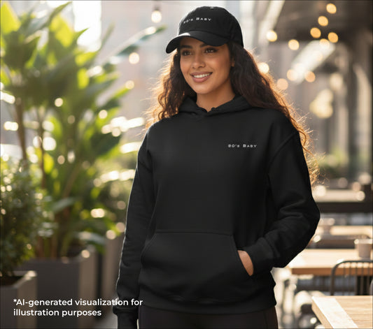 Woman wearing a black hoodie and cap with '90s baby' embroidered on them outdoors.