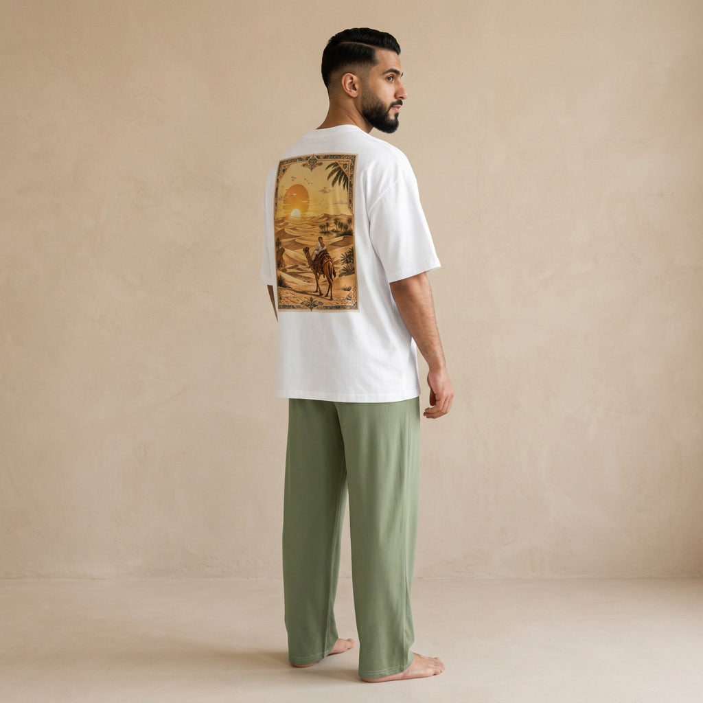 Model wearing a white oversized T-shirt with a desert camel graphic on the back and military green wide-leg pants, shown from behind.