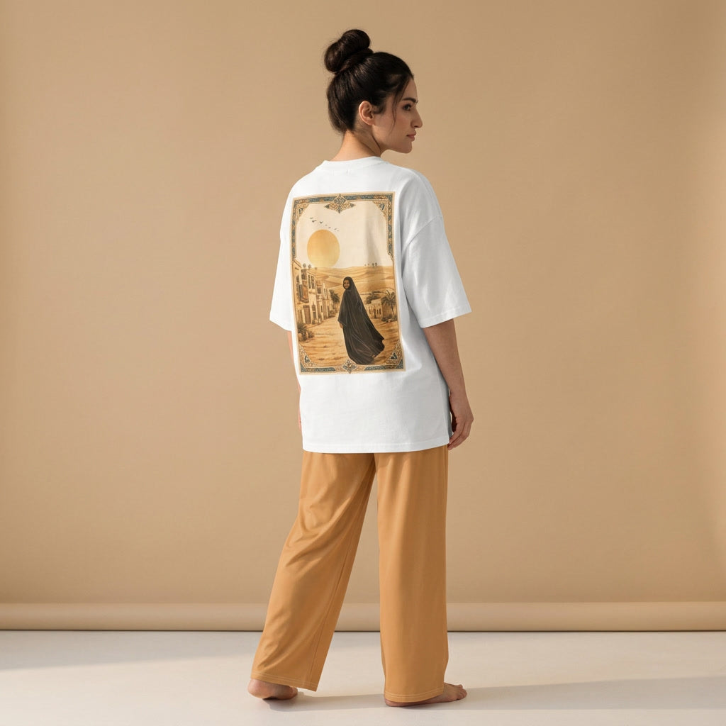 Model wearing a white oversized T-shirt with a sepia-toned illustration of a woman on the back and light brown wide-leg pants, viewed from behind.