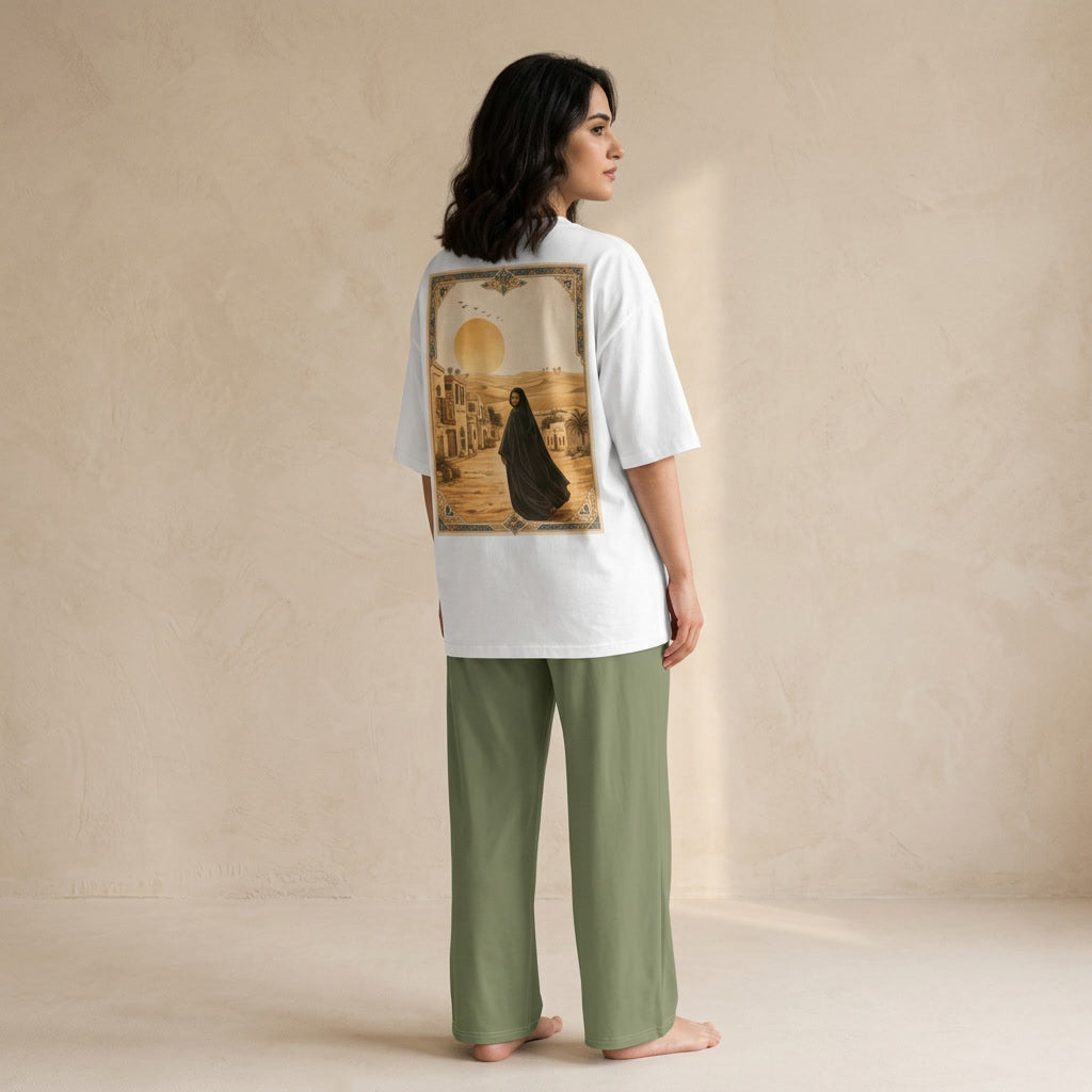 Rear view of a model wearing a white oversized T-shirt with A Woman’s Story artwork on the back and military green wide-leg pants.