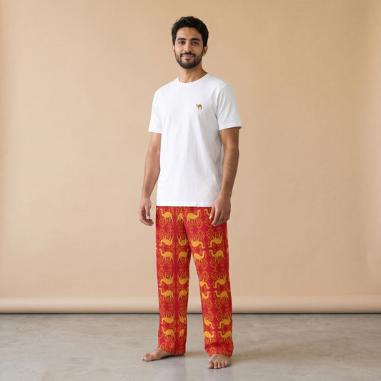 Model wearing a white camel motif T-shirt and red pants with golden camels and arabesque patterns, front view.