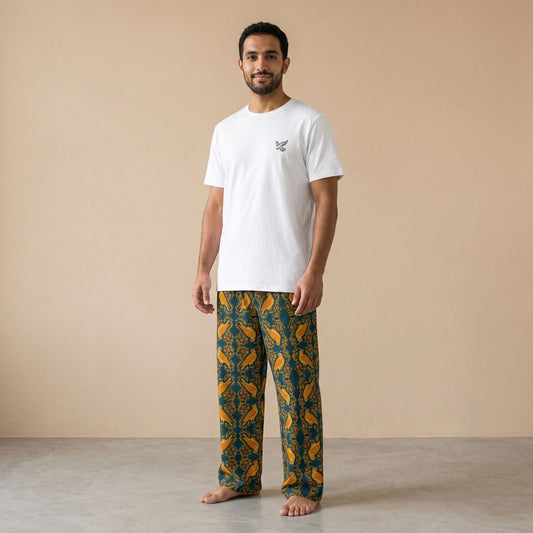 Model wearing a white falcon motif T-shirt and teal pants with golden falcons and arabesque patterns, front view.