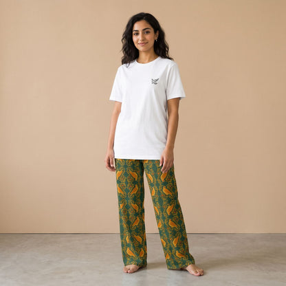 Model wearing a white falcon motif T-shirt and dark green pants with golden falcons and arabesque patterns, front view.