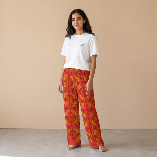 Model wearing a white falcon motif T-shirt and red pants with golden falcons and arabesque patterns, front view.