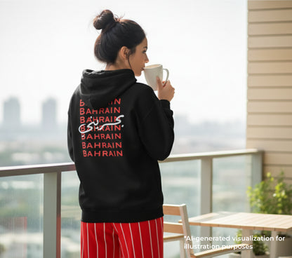 Woman wearing a black hoodie with 'BAHRAIN' text, holding a mug on a balcony.