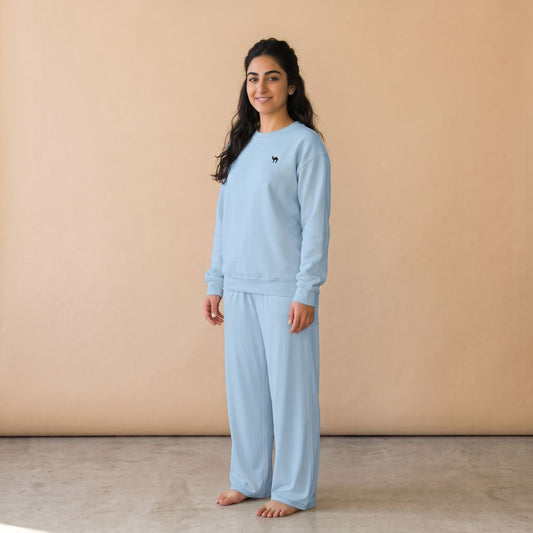 Model wearing a light blue sweatshirt with a small black camel motif and matching plain wide-leg pants, front view.