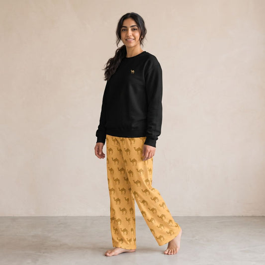 Model wearing a sand sweatshirt with small camel embroidery and yellow wide-leg pants with a repeating camel print.