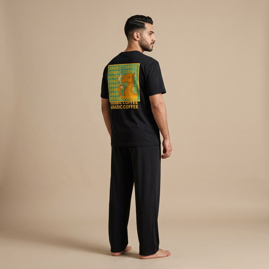 Model seen from behind wearing a black T-shirt with a camel and “Arabic Coffee” back graphic, paired with black wide-leg pants.