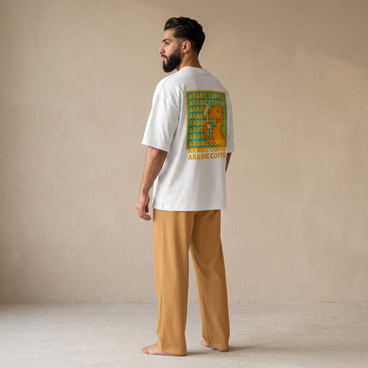 Model wearing a white oversized T-shirt with a camel and “Arabic Coffee” back graphic, paired with light brown wide-leg pants, viewed from behind.