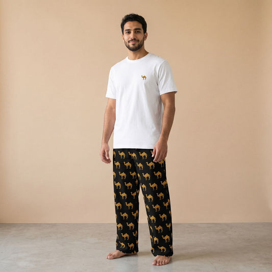 Model wearing a white T-shirt with a small camel motif and black pants with golden camel prints, front view.
