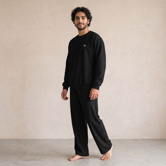 Model wearing a black sweatshirt with small camel embroidery on the chest and matching black wide-leg pants.