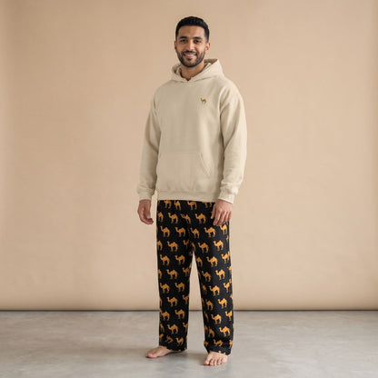 Model wearing a sand-coloured hoodie with a small camel motif and black pants with golden camel prints, front view.