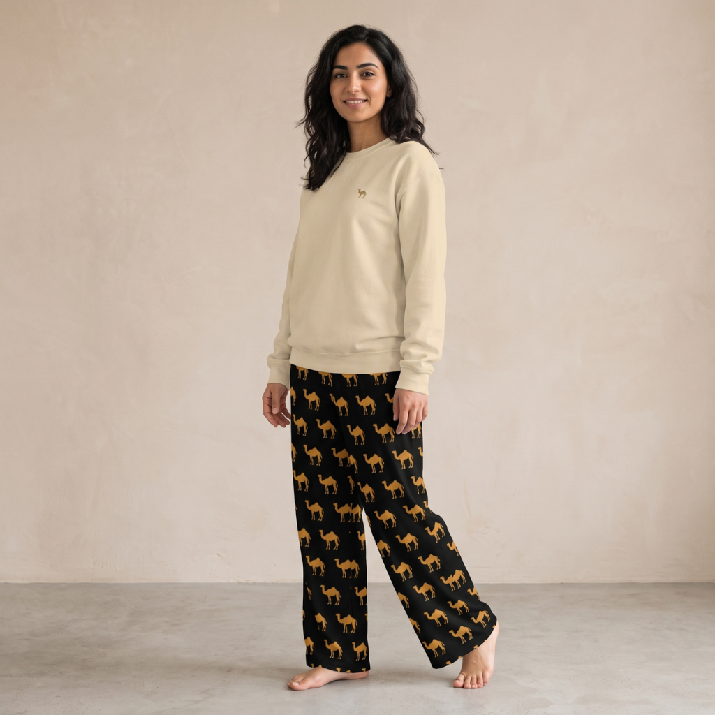 Model wearing a sand sweatshirt with small camel embroidery and black wide-leg pants with a repeating camel print.