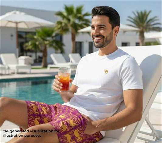 Man sitting by a pool holding a drink, with palm trees and a building in the background