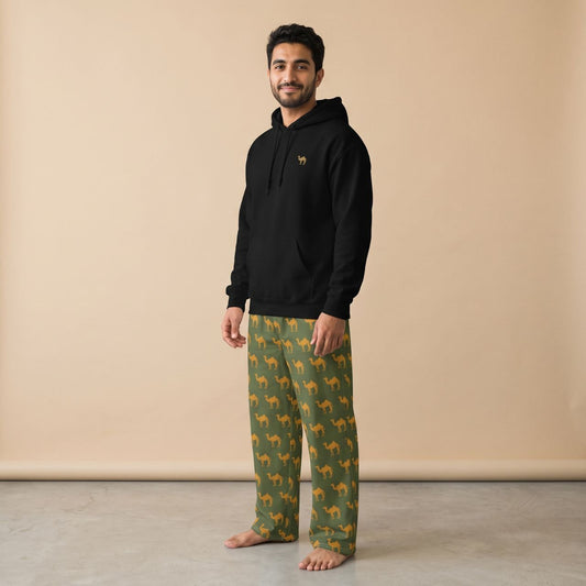 Model wearing a black hoodie with a small camel motif and olive green pants with golden camel prints, front view.