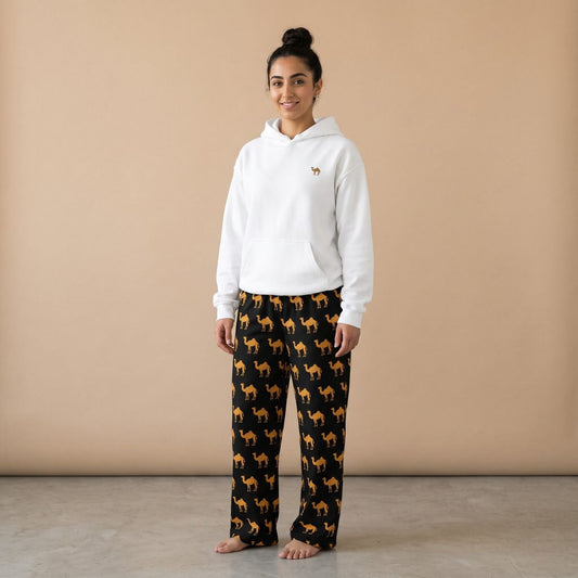 Model wearing a white hoodie with a small camel motif and black pants with golden camel prints, front view.