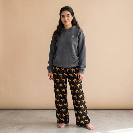 Model wearing a white hoodie with a small camel motif and black pants with golden camel prints, front view.