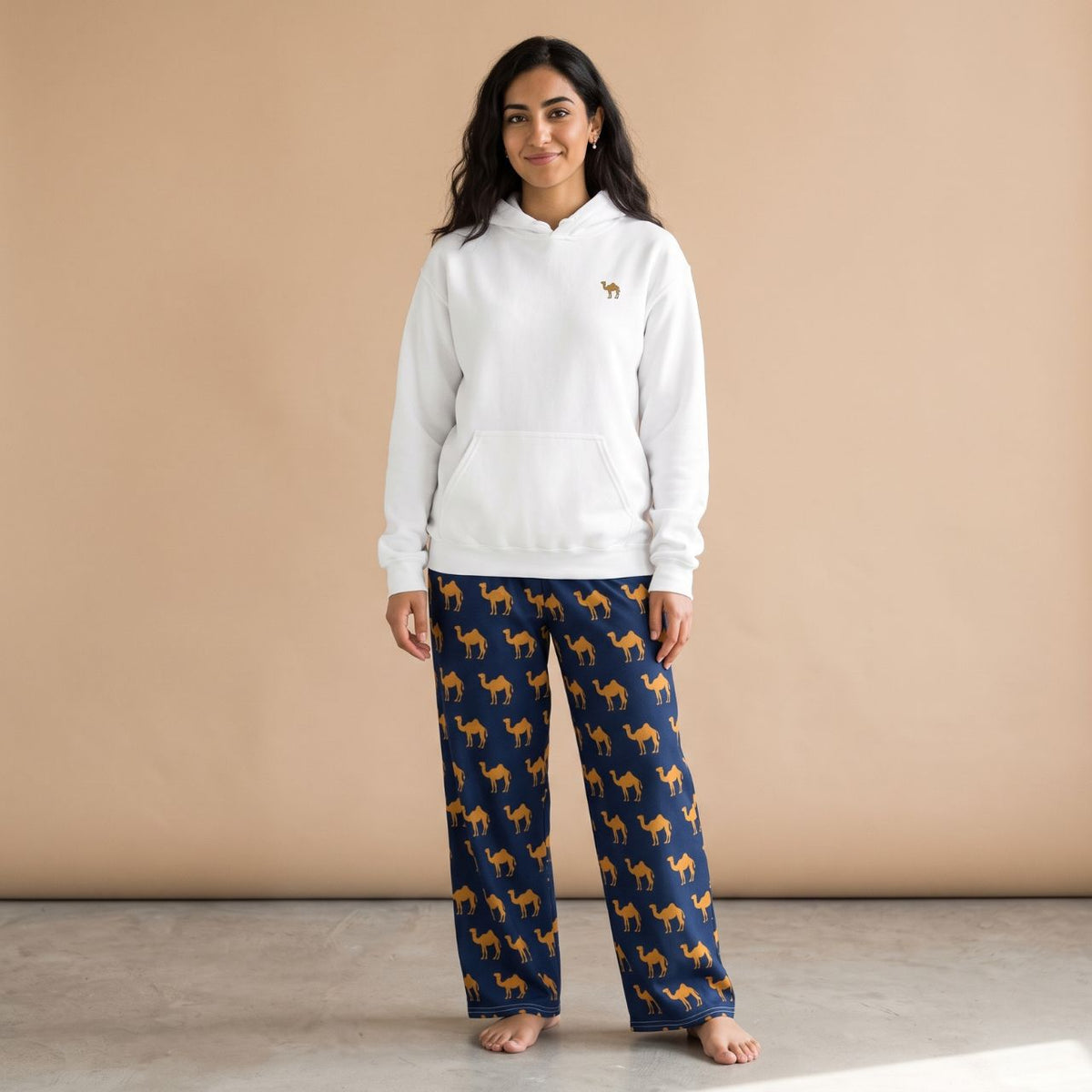 Model wearing a white hoodie with a small camel motif and navy blue pants with golden camel prints, front view.