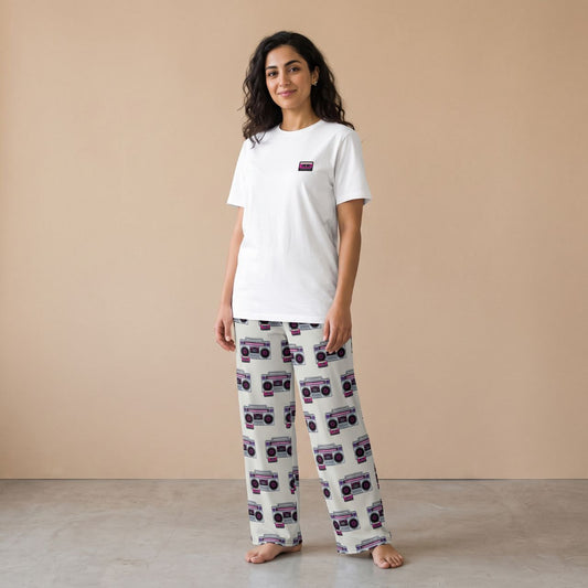 Model wearing a white T-shirt with a small cassette tape motif and cream pants with retro boombox prints, front view.