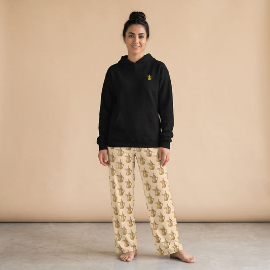 Model wearing a black hoodie with a small golden dallah motif and cream pants with Dallah pot prints, front view.