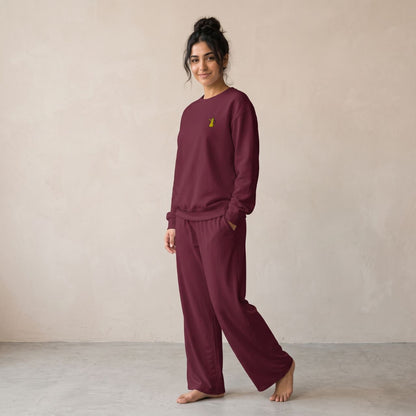 Model wearing a maroon sweatshirt with a small gold dallah coffee pot chest motif and matching wide-leg pants.