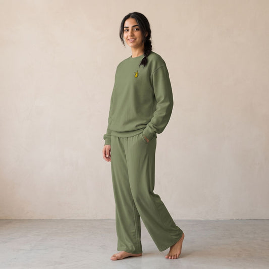 Model wearing a military green sweatshirt with a small gold dallah coffee pot chest motif and matching wide-leg pants.