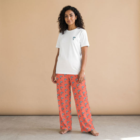 Model wearing a white T-shirt with a small dolphin motif and coral pants with blue dolphin prints, front view.