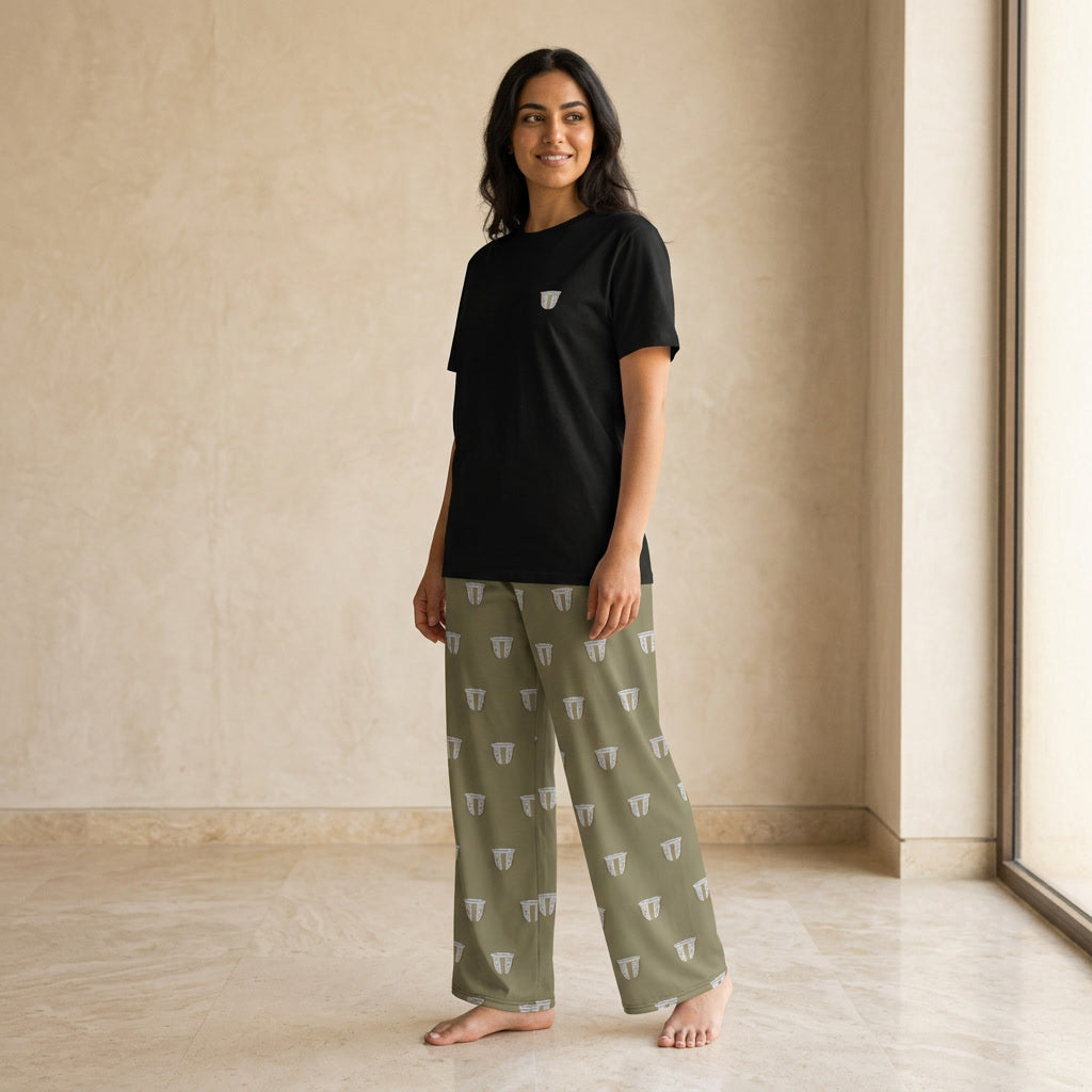 Woman wearing a black T-shirt with a small finjan cup motif and olive-green wide-leg pants with an all-over finjan cup print.