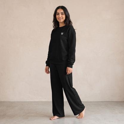 Model wearing a black Finjan sweatshirt with small Finjan cup embroidery on the chest and matching black wide-leg pants.