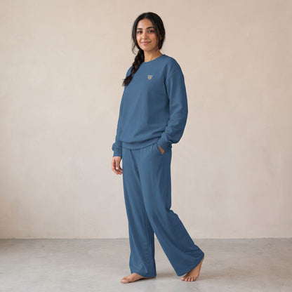 Model wearing an indigo blue sweatshirt with a small finjan coffee cup chest motif and matching wide-leg pants.