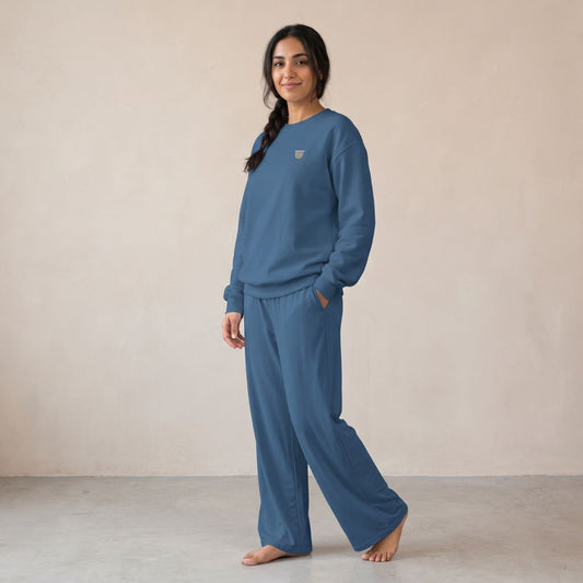 Model wearing an indigo blue sweatshirt with a small finjan coffee cup chest motif and matching wide-leg pants.