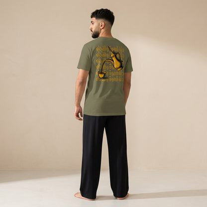 Model shown from behind wearing a khaki T-shirt with a gold dallah coffee pot, finjan cup and Arabic lettering on the back, paired with black wide-leg pants.