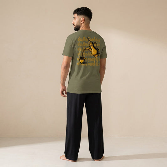 Model shown from behind wearing a khaki T-shirt with a gold dallah coffee pot, finjan cup and Arabic lettering on the back, paired with black wide-leg pants.