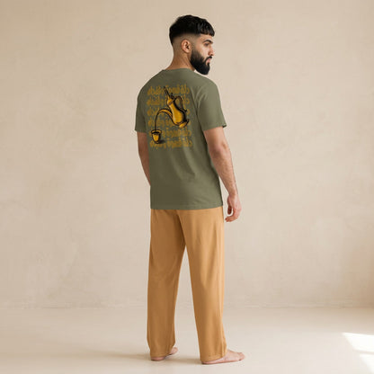 Model wearing a khaki T-shirt with a gold dallah and finjan graphic and Arabic lettering on the back, paired with light brown pants.