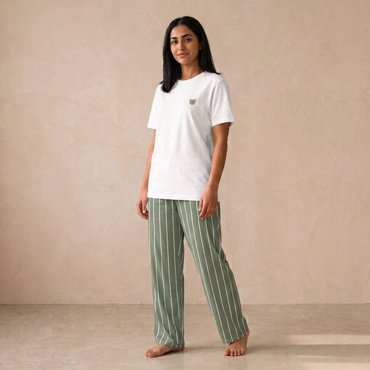 Model wearing a white T-shirt with a small finjan cup motif and sage green pants with white vertical stripes, front view.