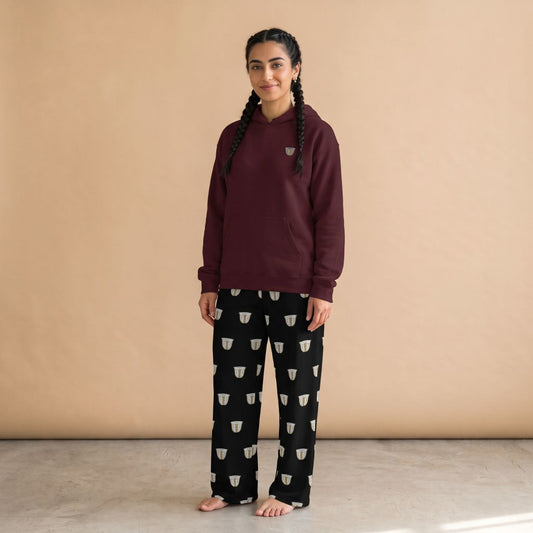 Model wearing a maroon hoodie with a small finjan cup motif and black pants with white finjan cup prints, front view.