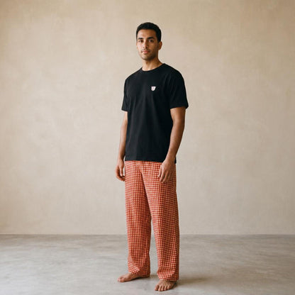 Model wearing a black Finjan T-shirt with a small chest motif and red and beige triangle-checkered wide-leg pants.