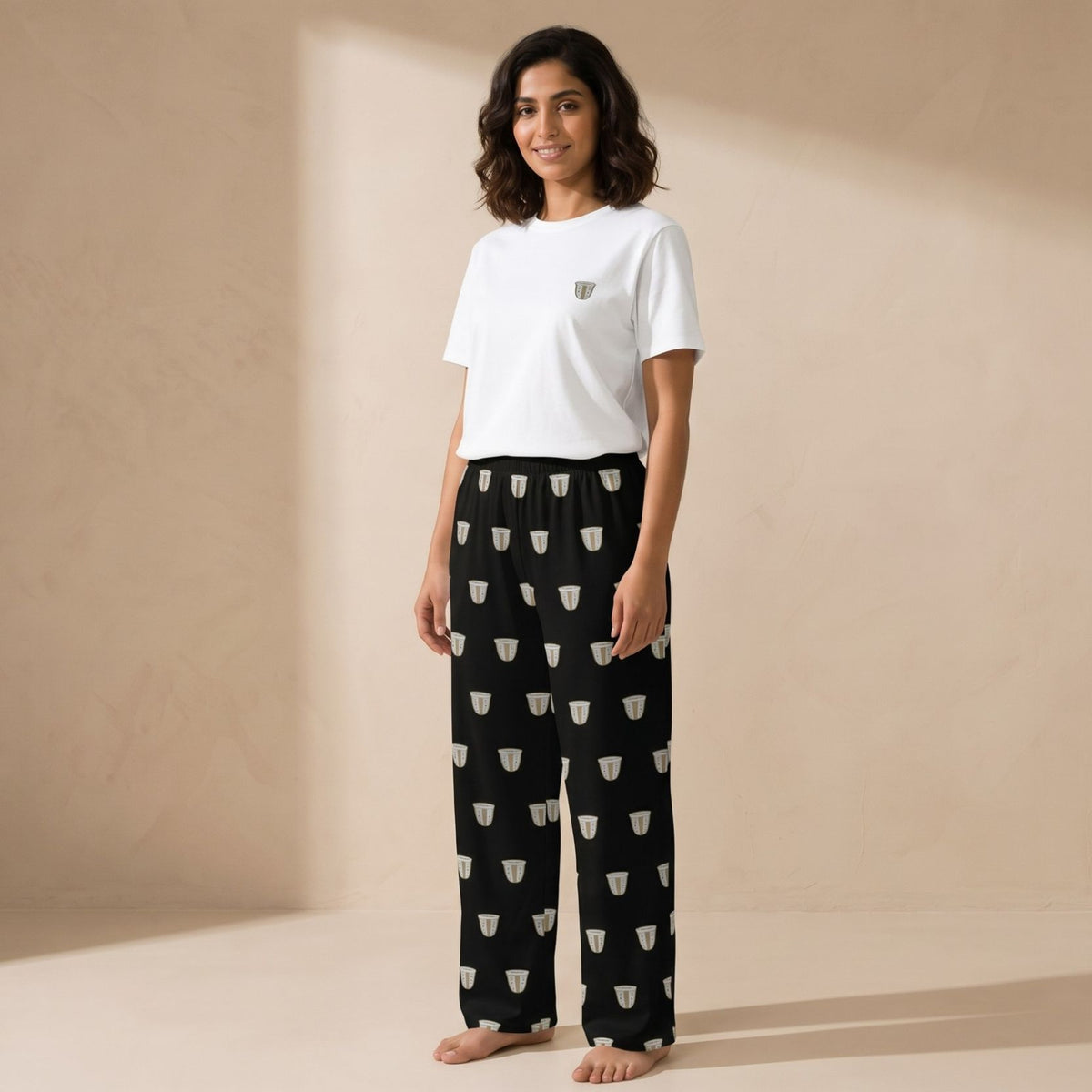 Model wearing the Finjan set: a white T-shirt with a small coffee cup motif and black wide-leg pants with a repeating white coffee cup print.