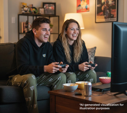 Two people playing video games in a living room with snacks and drinks on the coffee table.
