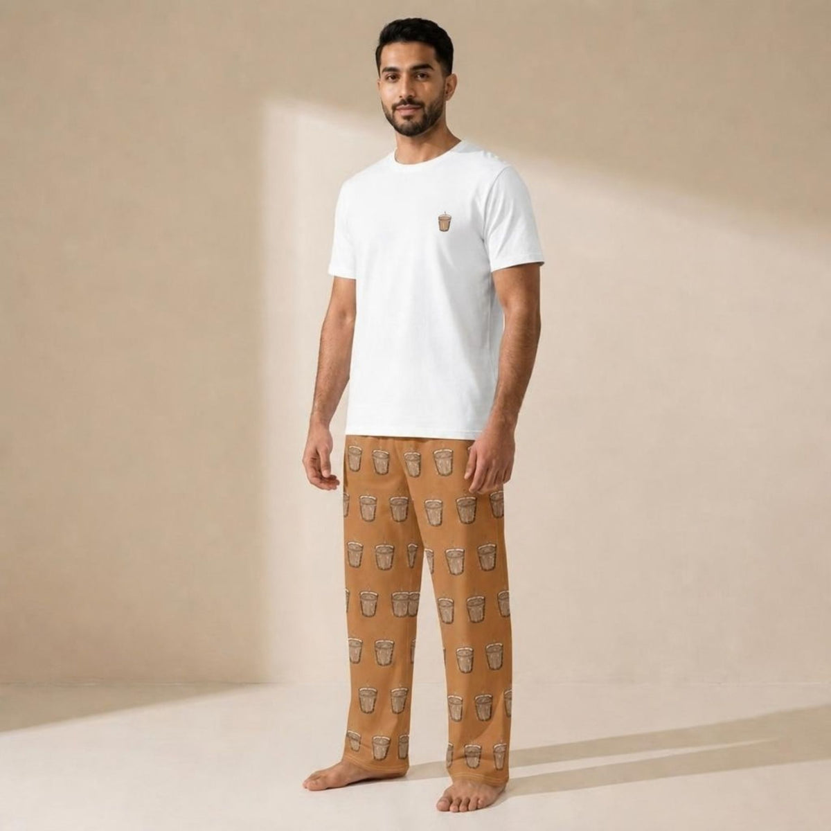 Model wearing a white Karak T-shirt with a small tea cup motif and tan pants patterned with tea cups.