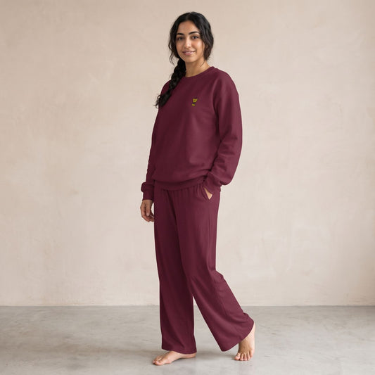 Model wearing a maroon sweatshirt with a small gold Mubkhar chest motif and matching wide-leg pants.