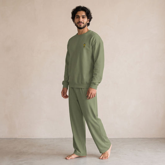 Model wearing a military green sweatshirt with a small gold Mubkhar chest motif and matching wide-leg pants.