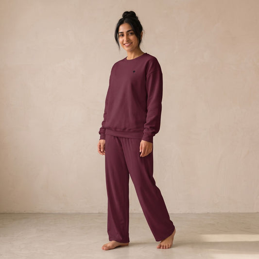 Model wearing a maroon sweatshirt with a small palm tree chest motif and matching wide-leg pants.