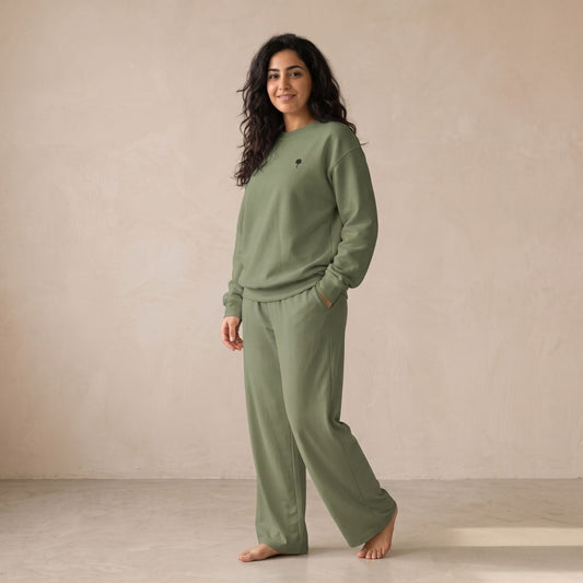 Model wearing a military green sweatshirt with a small palm tree chest motif and matching wide-leg pants.